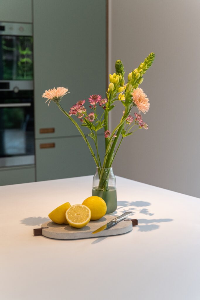 Aménagement de cuisine avec plan de travail en Corian, caissons IKEA personnalisés, matériaux Arpa Industriale et Fenix, design contemporain.
