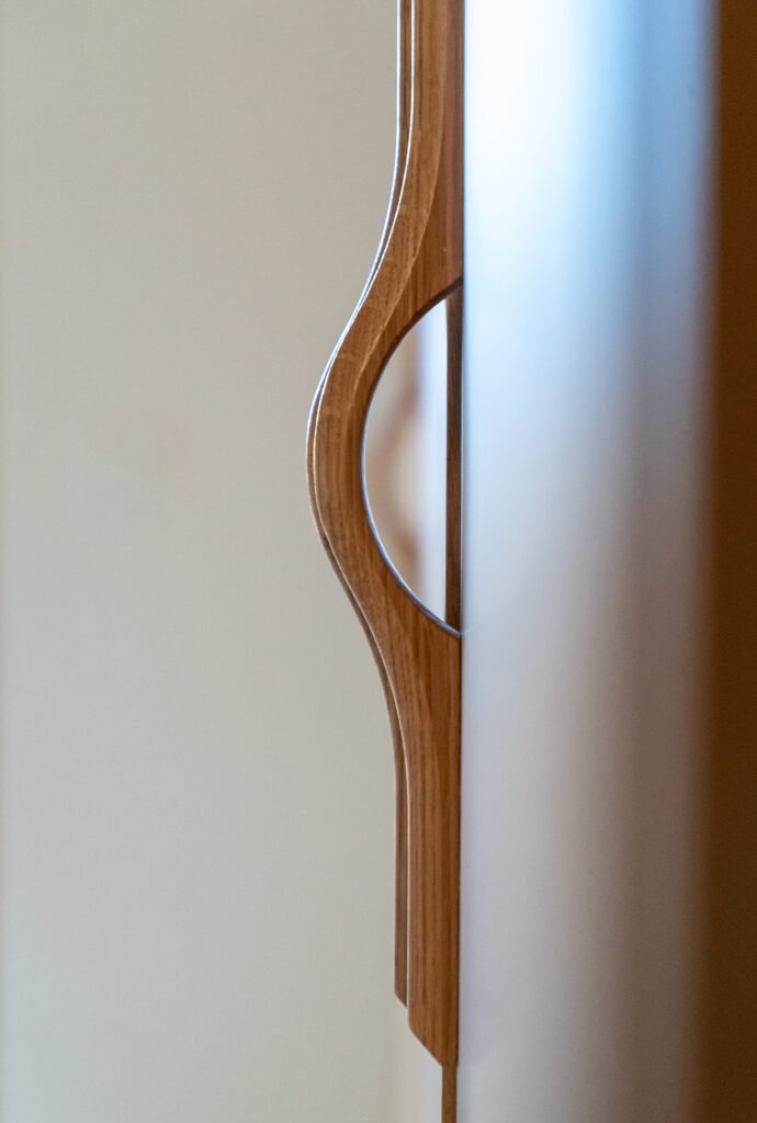 Détail de la poignée sculptée en bois sur une façade en chêne naturel du dressing sur-mesure Popline.
