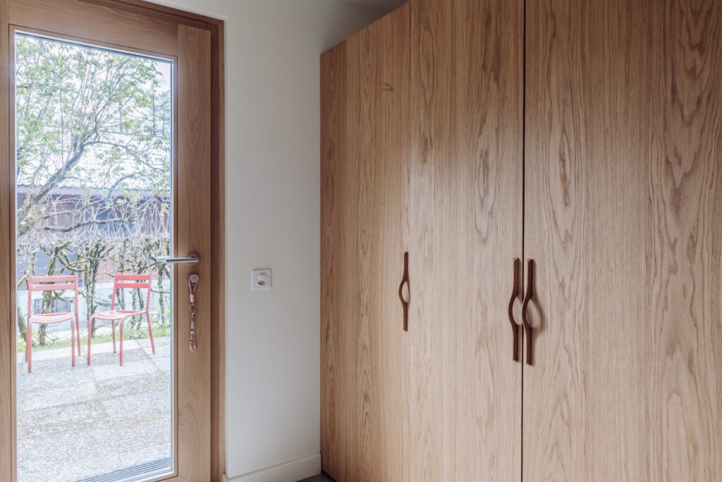 Dressing sur-mesure IKEA Pax avec des façades en chêne naturel Popline près d’une porte-fenêtre.