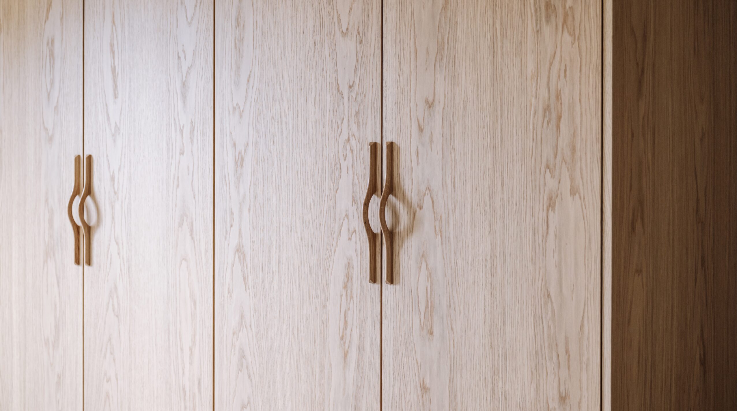 Façades en chêne naturel Popline sur un dressing sur-mesure IKEA Pax avec poignées sculptées.
