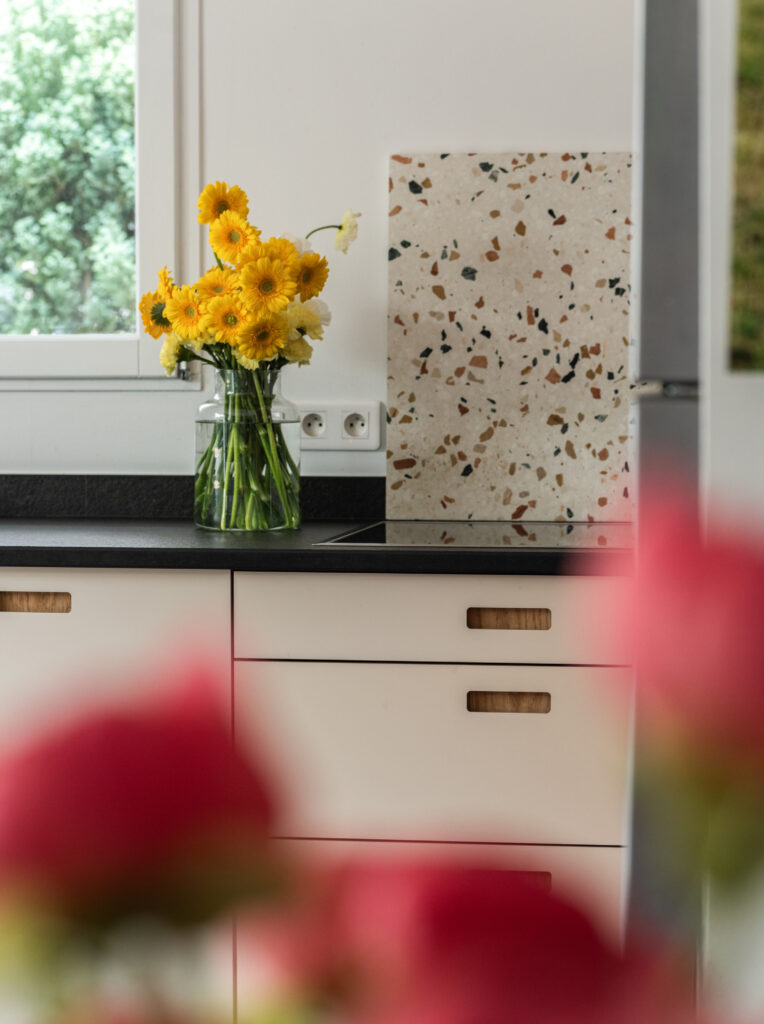 Bouquet de fleurs jaunes sur un plan de travail noir avec des façades Popline dans une cuisine rénovée IKEA Faktum.