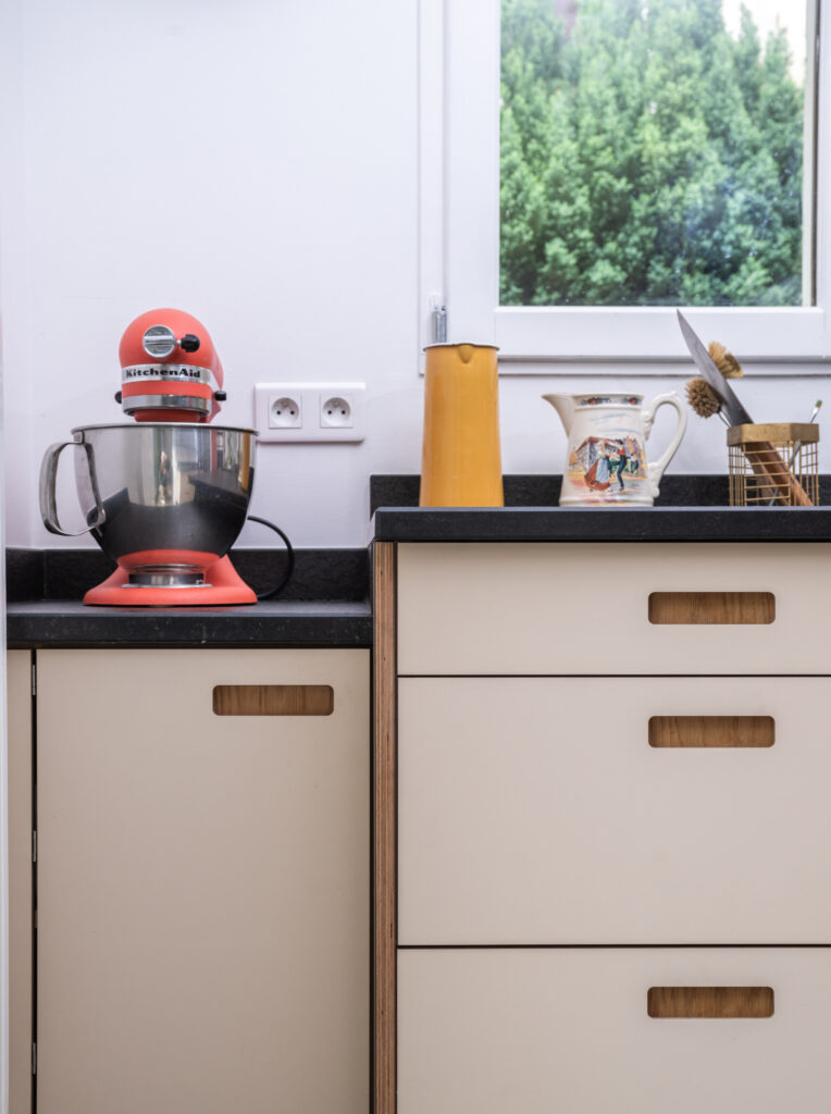 Mixeur KitchenAid rouge sur un plan de travail noir dans une cuisine Ikea Faktum rénovée avec des façades Popline beige.