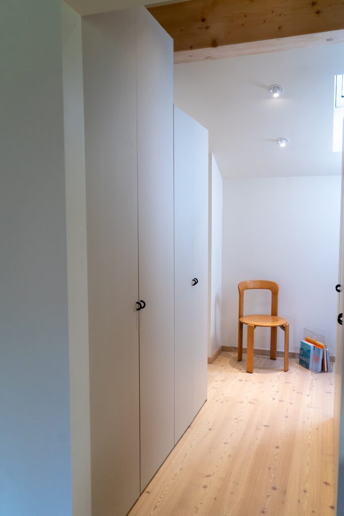 Vue latérale du dressing IKEA Pax sur-mesure avec façades UNI, installé dans un couloir d'un chalet jurassien.