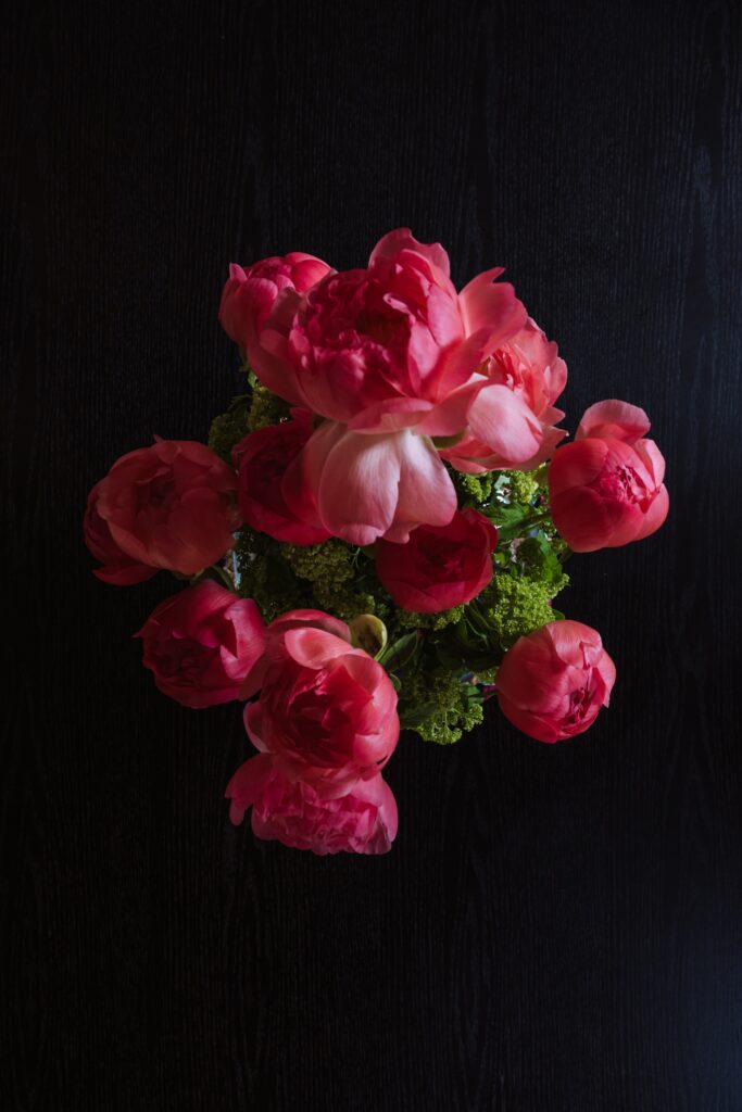 Fleurs roses sur une table noire avec un plan de travail en chêne foncé dans un chalet jurassien moderne